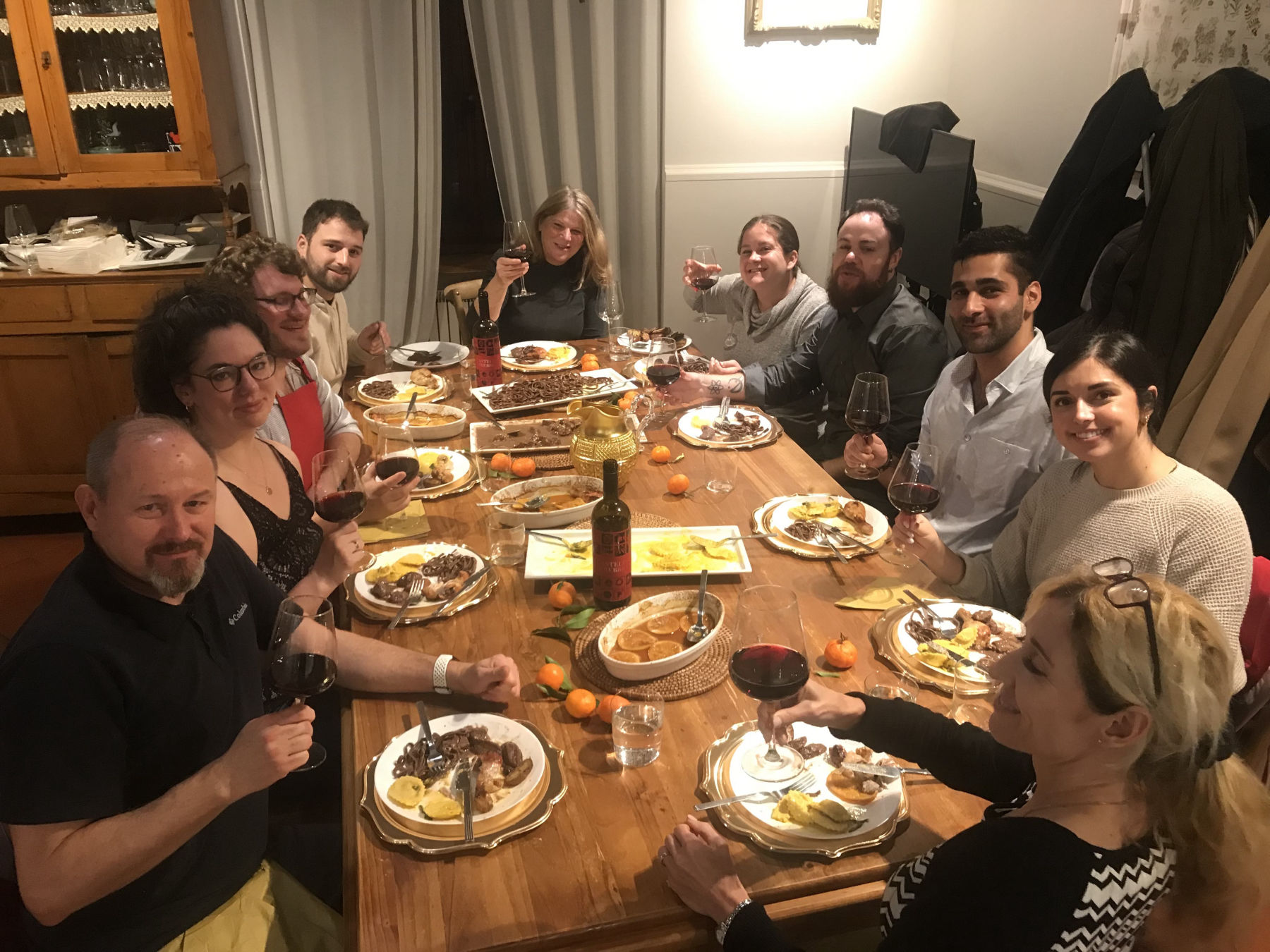 Dinner party guests toasting with wine over Italian feast